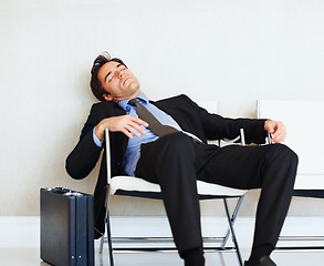 Image showing Business man, sleeping and case in airport, chair or fatigue from travel, overworked or burnout in suit. Entrepreneur, briefcase and tired for rest, exhausted or luggage for corporate job with stress