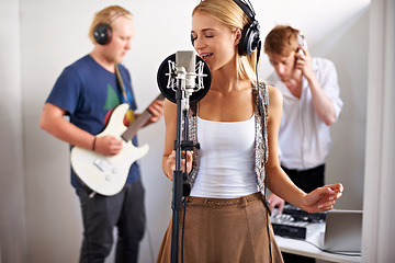 Image showing Professional, musician and woman with microphone, headphones and band performance with talent. Recording studio, art and girl singer live streaming for music record label, sound and audio broadcast.