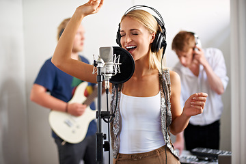 Image showing Professional, musician and happy woman with microphone, headphones and band performance with talent. Recording studio, art and girl singer live streaming for music label, sound and audio broadcast.