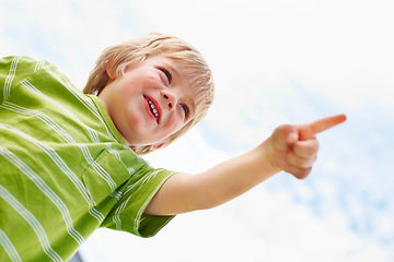 Image showing Boy, happy child and pointing at blue sky outdoor in low angle, summer mockup and show direction. Young cute kid, finger and hand gesture at clouds, playing and freedom for education below with smile