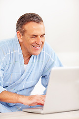 Image showing Bathrobe, morning and mature happy man on laptop for email, social media or streaming subscription on sofa. Internet search, couch and senior person on computer, website or networking in living room.