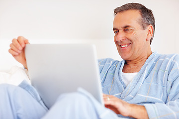 Image showing Bathrobe, relax and mature man on laptop for email, social media or streaming subscription on sofa. Internet search, couch and happy senior person on computer, website or networking in living room.