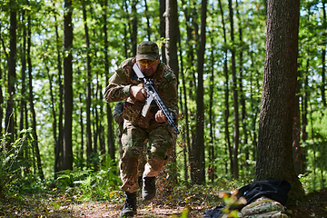 Image showing An elite soldier, camouflaged and stealthily navigating through dangerous woodland terrain, executes a covert mission in a secluded forest area