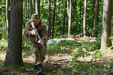 Image showing An elite soldier, camouflaged and stealthily navigating through dangerous woodland terrain, executes a covert mission in a secluded forest area