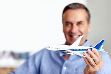 Image showing Mature man, flight and toy plane for travel, vacation and holiday planning with a smile at home. Happy, airplane model and retirement of a male person with confidence from trip and air traveling