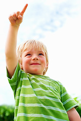 Image showing Boy, child and pointing at space outdoor in low angle, summer mockup and show direction. Young cute kid, finger and hand gesture at blue sky clouds, park and nature garden, playing and freedom