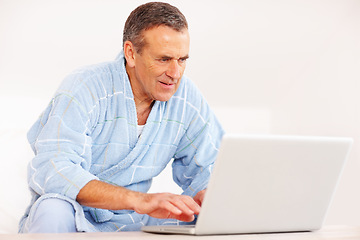 Image showing Bathrobe, morning and mature happy man on computer for email, social media or streaming subscription on sofa. Internet search, couch and senior person on laptop, website or networking in living room.