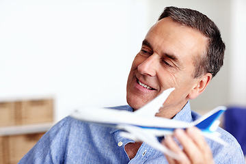 Image showing Business man, travel and toy plane for flight, vacation and holiday planning with a smile at home. Happy, airplane model and retirement of a male person with confidence from trip and air traveling