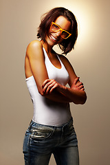 Image showing Fashion, smile and portrait of woman in a studio with casual, trendy and stylish outfit for confidence. Happy, glasses and young female person from Canada with cool style isolated by brown background