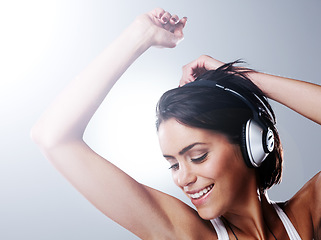 Image showing Music, dance and happy woman with headphones in studio with freedom, party and celebration. Dancer, performance and person listening to audio track, song and radio for movement on gray background