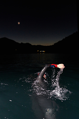 Image showing A determined professional triathlete undergoes rigorous night time training in cold waters, showcasing dedication and resilience in preparation for an upcoming triathlon swim competition