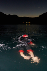 Image showing A determined professional triathlete undergoes rigorous night time training in cold waters, showcasing dedication and resilience in preparation for an upcoming triathlon swim competition