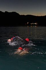 Image showing A determined professional triathlete undergoes rigorous night time training in cold waters, showcasing dedication and resilience in preparation for an upcoming triathlon swim competition