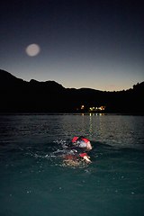 Image showing A determined professional triathlete undergoes rigorous night time training in cold waters, showcasing dedication and resilience in preparation for an upcoming triathlon swim competition