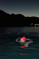 Image showing A determined professional triathlete undergoes rigorous night time training in cold waters, showcasing dedication and resilience in preparation for an upcoming triathlon swim competition