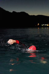 Image showing A determined professional triathlete undergoes rigorous night time training in cold waters, showcasing dedication and resilience in preparation for an upcoming triathlon swim competition