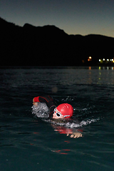 Image showing A determined professional triathlete undergoes rigorous night time training in cold waters, showcasing dedication and resilience in preparation for an upcoming triathlon swim competition