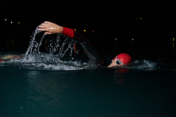 Image showing A determined professional triathlete undergoes rigorous night time training in cold waters, showcasing dedication and resilience in preparation for an upcoming triathlon swim competition