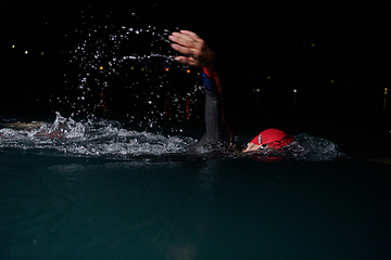 Image showing A determined professional triathlete undergoes rigorous night time training in cold waters, showcasing dedication and resilience in preparation for an upcoming triathlon swim competition