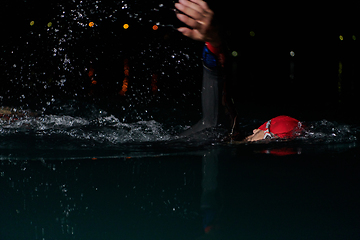 Image showing A determined professional triathlete undergoes rigorous night time training in cold waters, showcasing dedication and resilience in preparation for an upcoming triathlon swim competition