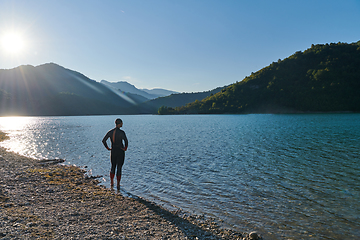 Image showing Authentic triathlon athlete getting ready for swimming training on lake