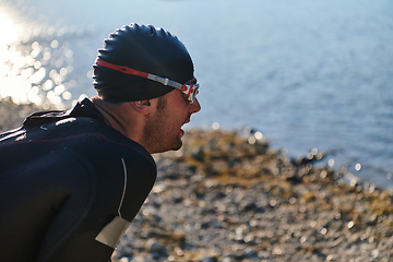 Image showing Authentic triathlon athlete getting ready for swimming training on lake