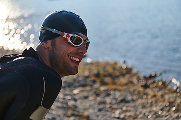 Image showing Authentic triathlon athlete getting ready for swimming training on lake