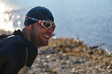 Image showing Authentic triathlon athlete getting ready for swimming training on lake