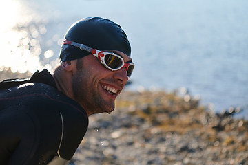 Image showing Authentic triathlon athlete getting ready for swimming training on lake