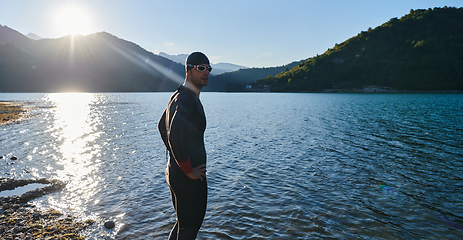 Image showing Authentic triathlon athlete getting ready for swimming training on lake