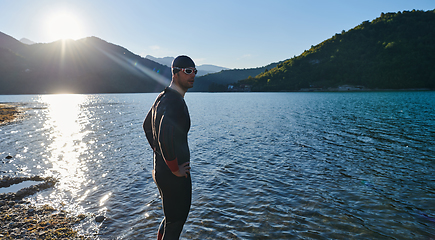 Image showing Authentic triathlon athlete getting ready for swimming training on lake