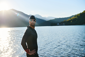 Image showing Authentic triathlon athlete getting ready for swimming training on lake