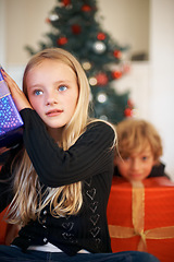 Image showing Christmas, listening and a girl opening a present under a tree in the morning for celebration or tradition. Kids, gift and festive with an adorable young child in the living room of her home
