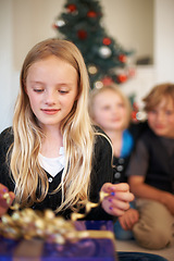 Image showing Girl, gift or unwrap ribbon in festive season with happiness, christmas tree or excited siblings in living room. Children, surprise or smile for presents in house, together or celebration on holiday
