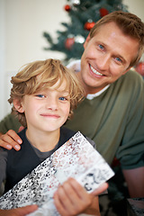 Image showing Boy, gift and father in portrait for festive season sharing, love together and excited in living room. Child, man and smile face for presents in house, bonding and celebration with care on holiday