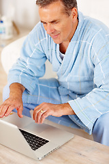 Image showing Bathrobe, morning and mature man on laptop, checking email, social media or streaming subscription on sofa. Internet search, couch and senior person on computer, website or networking in living room.