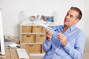 Image showing Mature man, thinking and toy plane for travel, vacation and holiday planning with a smile at home. Happy, airplane model and retirement of a male person with confidence from trip and air traveling