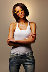 Image showing Fashion, happy and portrait of woman in a studio with casual, trendy and stylish outfit for confidence. Smile, glasses and young female person from Canada with cool style isolated by brown background