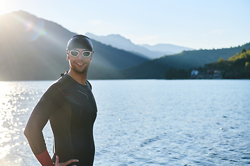 Image showing Authentic triathlon athlete getting ready for swimming training on lake