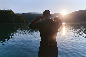 Image showing Authentic triathlon athlete getting ready for swimming training on lake