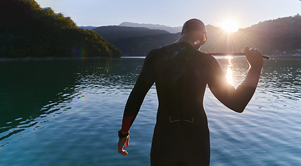 Image showing Authentic triathlon athlete getting ready for swimming training on lake