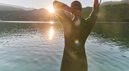 Image showing Authentic triathlon athlete getting ready for swimming training on lake