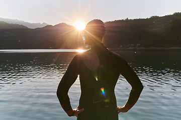 Image showing Authentic triathlon athlete getting ready for swimming training on lake