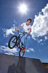 Image showing Ride, bike and teenager on ramp for sport performance, jump or training for event at park with blue sky mockup. Bicycle, stunt or balance on edge of board in trick for cycling competition challenge