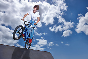 Image showing Riding, bike and teen on ramp for sport performance, jump or training for event at park with blue sky mockup. Bicycle, stunt or kid balance on edge of board in trick for cycling competition challenge