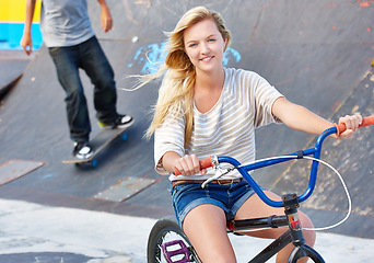 Image showing Ride, bike and portrait of teenager at skatepark in summer with friends on vacation or holiday with adventure. Girl, relax and enjoy exercise on bicycle with a smile for sports, event or fun in city