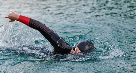 Image showing A professional triathlete trains with unwavering dedication for an upcoming competition at a lake, emanating a sense of athleticism and profound commitment to excellence.