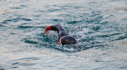 Image showing A professional triathlete trains with unwavering dedication for an upcoming competition at a lake, emanating a sense of athleticism and profound commitment to excellence.