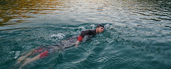 Image showing A professional triathlete trains with unwavering dedication for an upcoming competition at a lake, emanating a sense of athleticism and profound commitment to excellence.