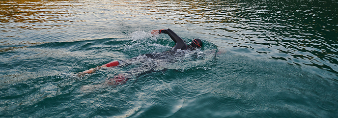 Image showing A professional triathlete trains with unwavering dedication for an upcoming competition at a lake, emanating a sense of athleticism and profound commitment to excellence.